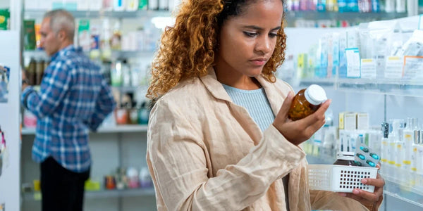 woman in pharmacy looking in bottle of pills